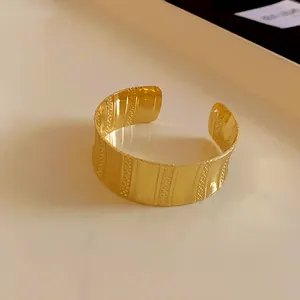 Detailed view of golden wide open cuff bracelet featuring elegant vertical textures