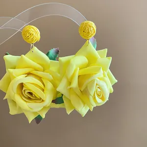 Vista de detalle de elegantes pendientes hechos a mano de rosa de tela amarilla y rafia