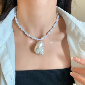 Dettaglio di una collana di perle barocche con un grande ciondolo a conchiglia naturale.