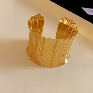 Detail view of a luxury wide gold-plated open cuff bracelet with vertical textures