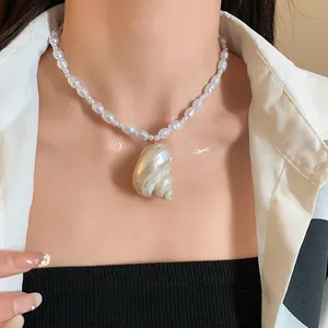 Dettaglio di una collana di perle barocche con un grande ciondolo a conchiglia su un modello.