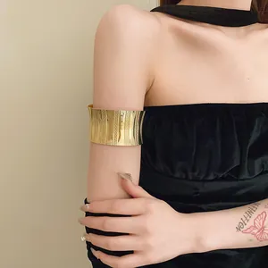Detail view of a textured light luxury gold metal wide cuff armlet worn on the upper arm