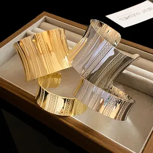 Close-up of gold and silver textured wide cuff bracelets in a jewelry box