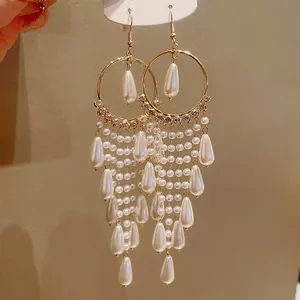 Close-up of elegant long tassel earrings with pearls and sparkling zircons
