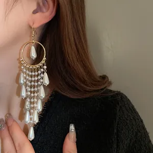 Close-up of elegant long tassel earrings with pearls and zircon on model's ear