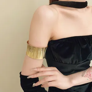 Minimalist gold metallic open arm cuff with vertical ribbed pattern on model