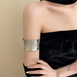 Wide metallic silver open cuff armlet jewelry worn on upper arm for edgy fashion.