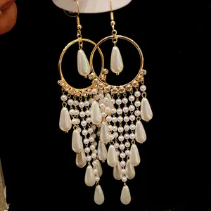 Detailed macro view of elegant long tassel earrings with white pearls and gold hoops.
