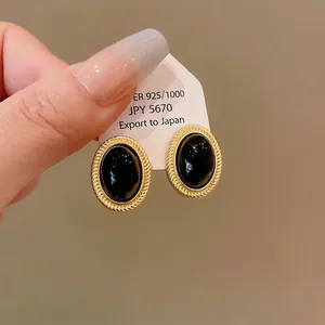 Vintage style gold-tone oval earrings with black onyx-style cabochon on white card