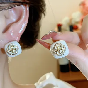 Close-up of elegant square zircon flower stud earrings with white enamel finish