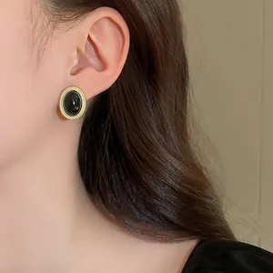 Detailed view of vintage oval black and gold earring featuring a textured metallic border.