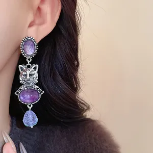 Detailed close-up of a vintage silver cat dangle earring with purple stones worn on the ear