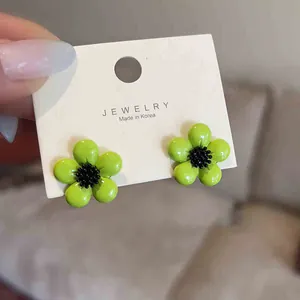 Macro view of green flower resin stud earrings with black center on display card