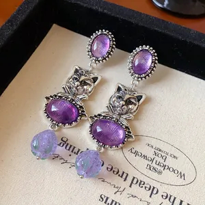 Close-up detail of vintage silver cat drop earrings with purple stones and beads