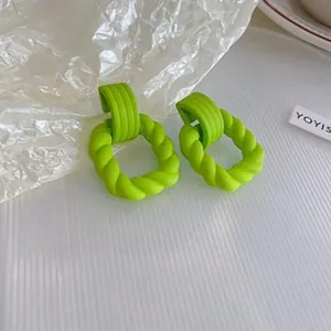 Close-up of vibrant lime green twisted resin hoop earrings with a matte spray finish