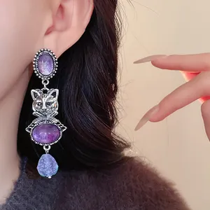 Close-up of vintage silver cat earrings with purple stones on an Asian model.