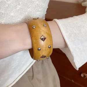 Close-up detail of a vintage-style wooden bangle featuring decorative silver metallic studs