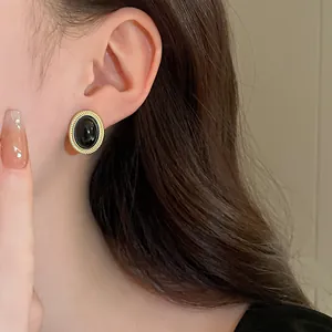 Close-up of a vintage oval earring featuring a black cabochon and gold twisted rope border.