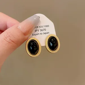 Detail of vintage oval earrings with black cabochon and gold rope border on card