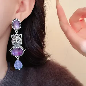 Macro detail of a vintage style silver cat drop earring featuring elegant purple stones