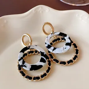 Elegant retro geometric round earrings featuring black and white marble pattern and gold chain detail