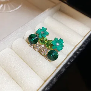 Close-up of green floral and round resin earrings inside a white jewelry box detailing