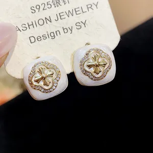 Detailed macro shot of elegant square zircon floral stud earrings with white enamel finish