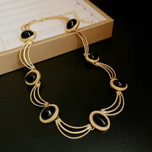Detailed view of a vintage oval geometric necklace with black stones in gold-toned settings.