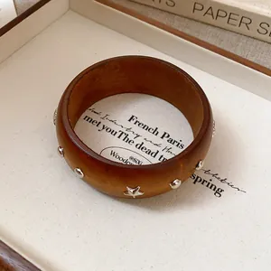 Close-up detail of retro wooden bangle featuring elegant silver star and round metal studs