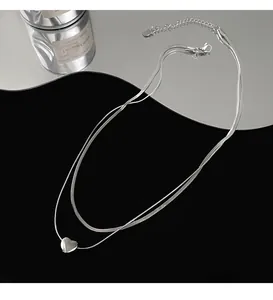 Detailed view of silver double-layered snake bone chain necklace with sleek heart pendant