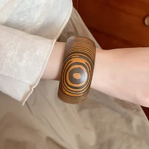 Detailed close-up of a retro wooden bangle with concentric grain pattern worn on a wrist.