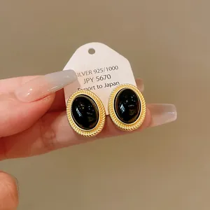 Close-up of vintage gold oval earrings with black center on a display card
