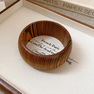 Detailed close-up of a vintage wooden bangle featuring unique natural striped grain patterns