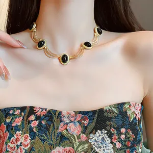 Detailed view of a vintage gold necklace with elegant black oval stones worn by a model.