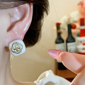 Detailed close-up of elegant zircon flower square earrings worn on a model's ear
