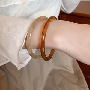 Close-up detail view of retro wood texture bangles in amber and beige colors on a wrist