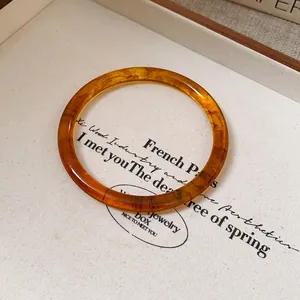 Detailed macro view of a vintage amber-colored bangle featuring elegant wooden grain texture