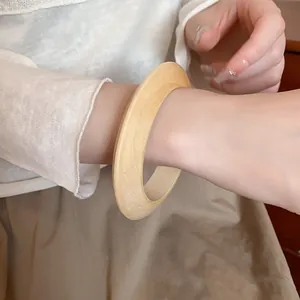Close-up of minimalist wooden bangle featuring natural wood grain texture on wrist