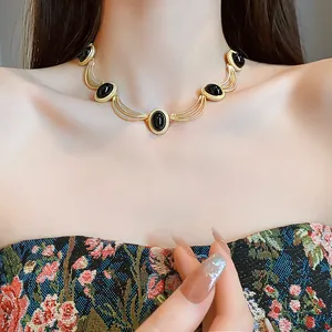 Close-up detail of a vintage gold necklace with black oval stones and elegant engraving