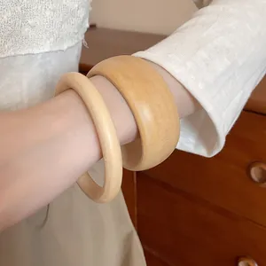 Close-up detail of two vintage-style wooden bangles in natural finish.