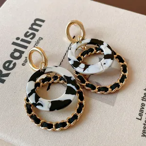 Close-up of vintage geometric round earrings with marble pattern and chain detail