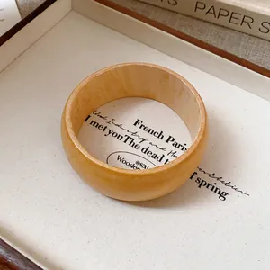 Detailed view of a wide wooden texture bangle with natural grain on a cream tray.