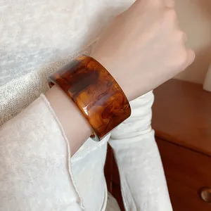 Close-up of a vintage tortoiseshell resin cuff bracelet with brown wood grain pattern