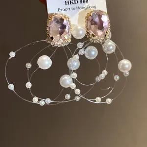 Dettaglio macro di orecchini vintage francesi con cristalli rosa e perle a strati.