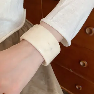 Detailed view of a vintage cream wood texture wide resin bangle worn on a wrist