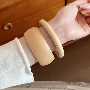Close-up of two natural wood grain bracelets worn on a wrist for a retro look.