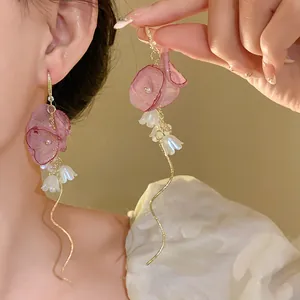 Detailed view of elegant pink chiffon flower bud and pearl tassel hook earrings worn on ear