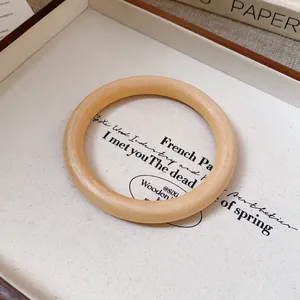 Close-up of minimalist wood grain texture bangle bracelet on aesthetic background.