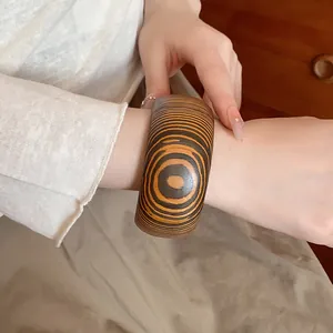 Close-up of a vintage-style wooden bangle featuring a unique concentric grain pattern design