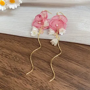 Close-up of elegant chiffon flower tassel earrings with white pearls and gold wavy chains
